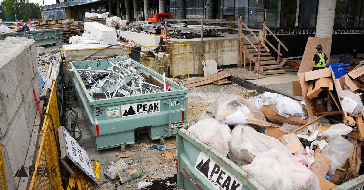 Construction site with Peak Disposal's roll-off dumpsters filled with debris and building materials on a busy urban job site.