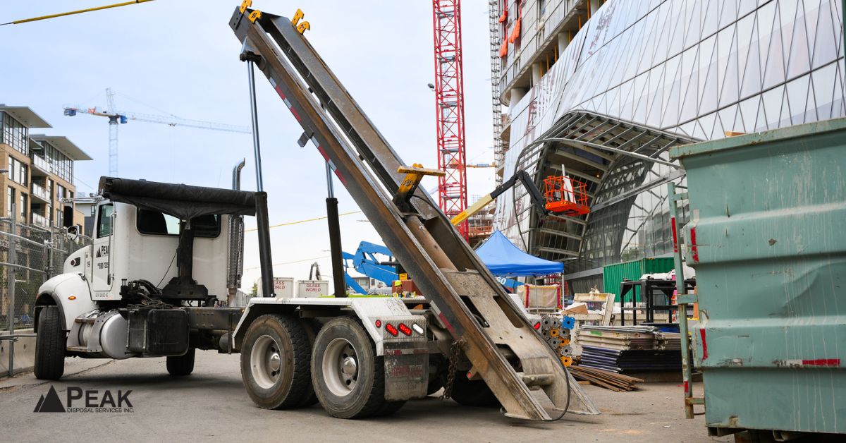 Roll-off dumpster truck delivering container at active construction site, helping match appropriate waste bin capacity and requirements.