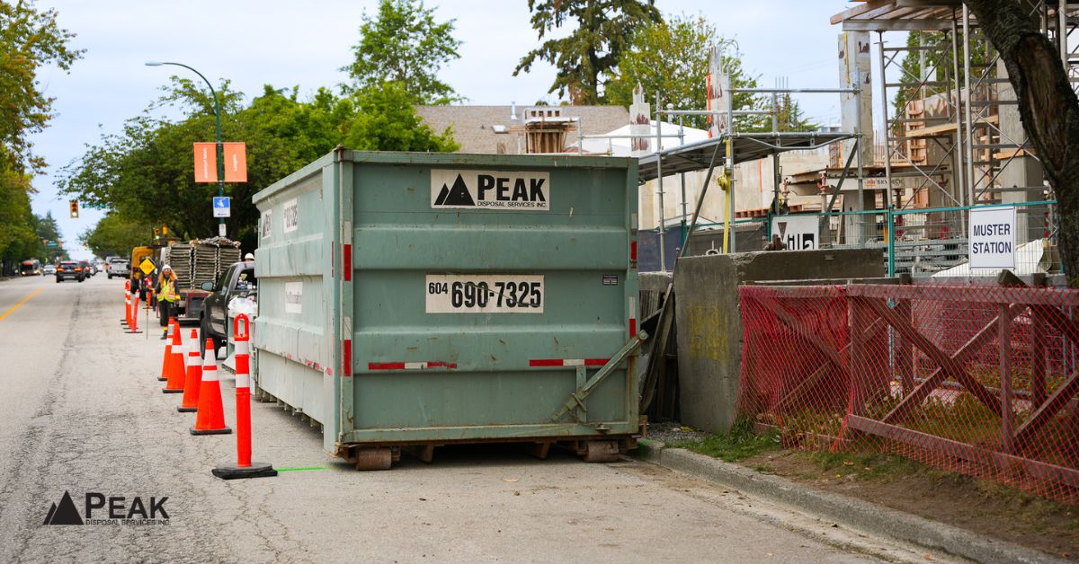 Peak Disposal dumpster sits near construction cones and worksite fencing, ready for project-specific waste bin placement support.