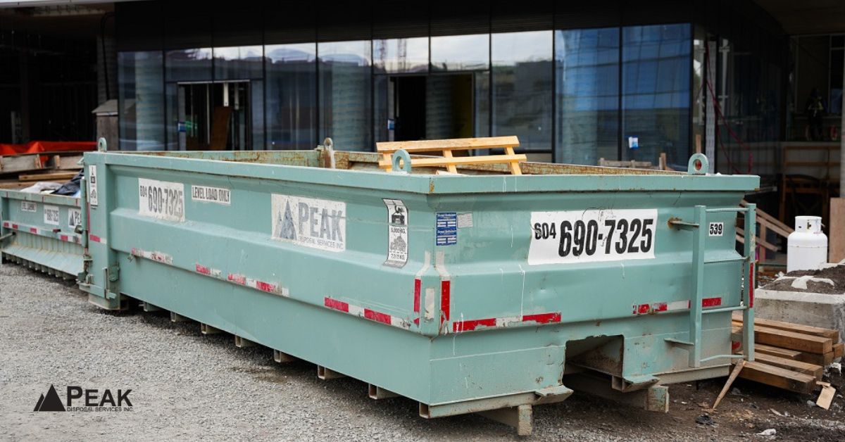Large construction dumpster at commercial job site supporting organized wood waste recycling and coordinated debris disposal operations.