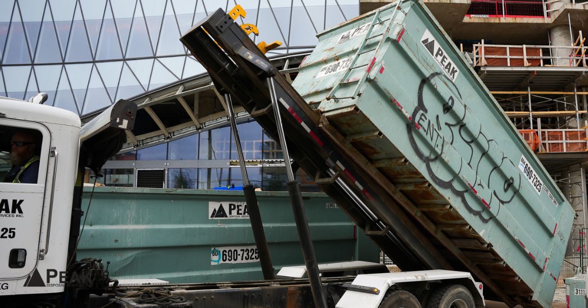 Roll-off dumpster delivery truck positions container at construction site, demonstrating professional placement for efficient waste management and project support.