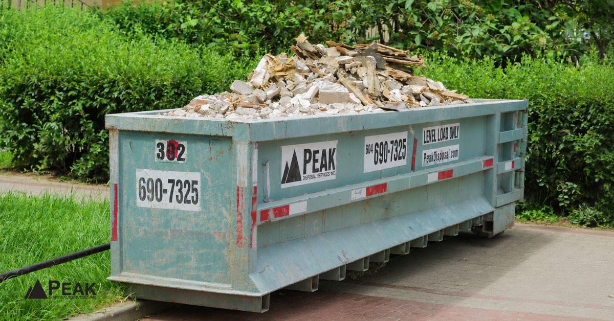 Teal dumpster loaded with concrete debris outdoors shows when professional disposal becomes worth it for major projects.