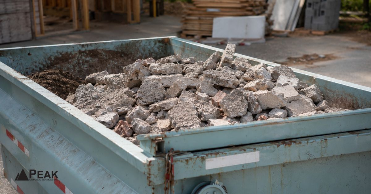 dumpster filled with concrete debris at an outdoor construction site with materials nearby.